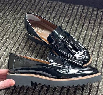 A pair of shiny black loafers with tassels