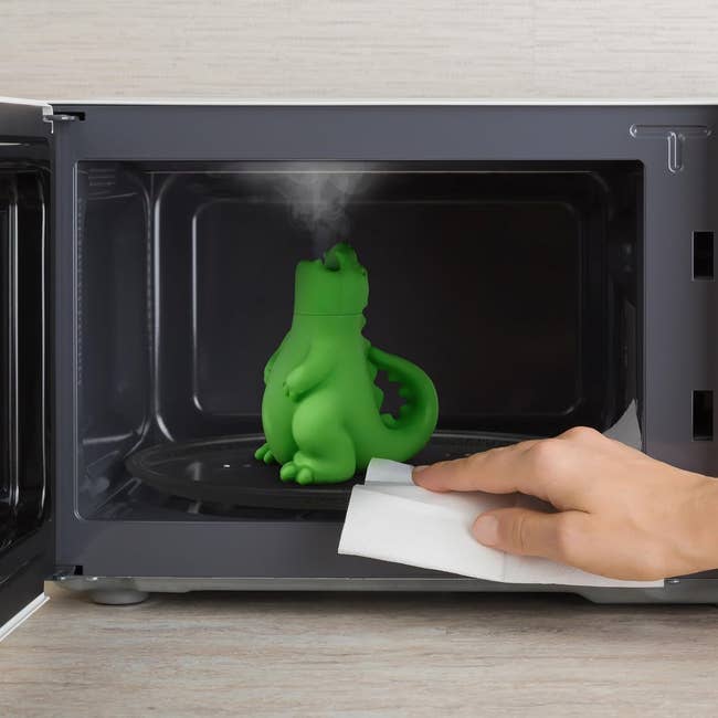 Green dinosaur-shaped microwave cleaner steaming wrong a microwave
