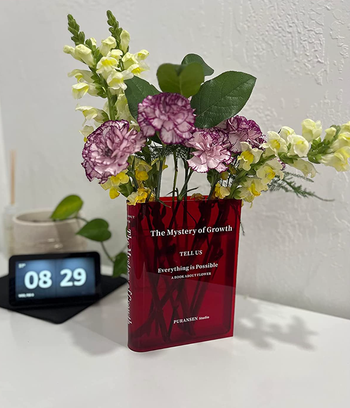 A clear red version of the base with colorful flowers propped on a desk 