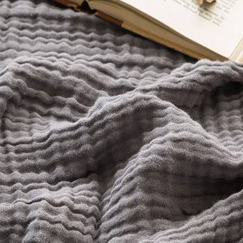 a close up of the texture of the grey throw blanket