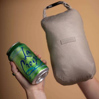 model holding blanket folded up next to a can of La Croix