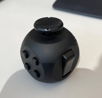 Reviewer image of black fidget cube on desk