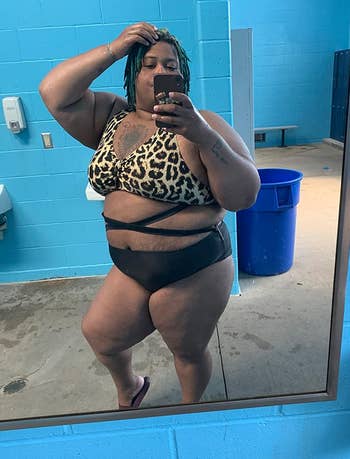 a reviewer wearing the bathing suit with an animal print upper half and solid black bottom half 