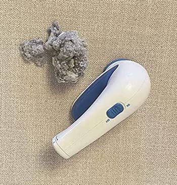 reviewer photo of the fabric shaver next to a pile of lint it removed from a couch