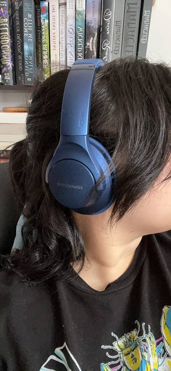 a reviewer wearing the blue pair of headphones