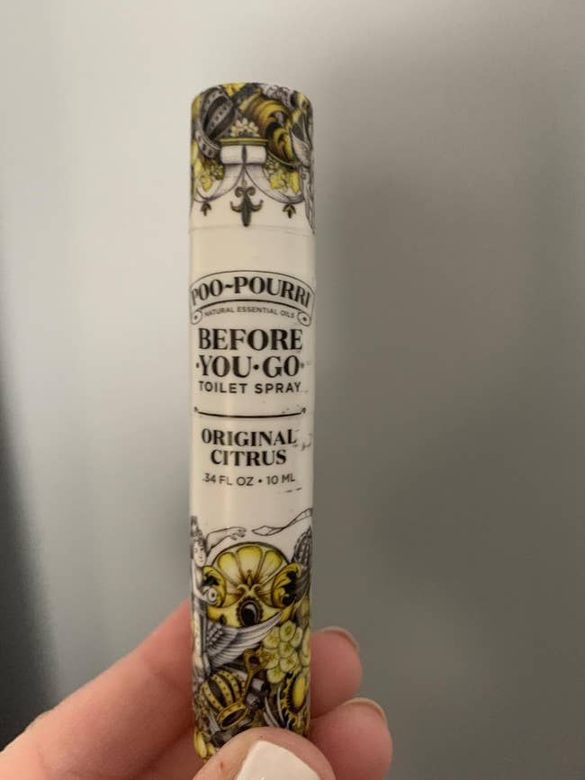 A reviewer holding the poopouri spray