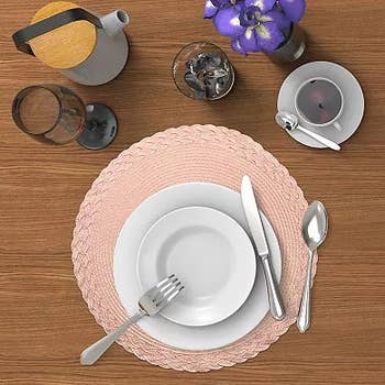 a pink placemat under a plate set and utensils