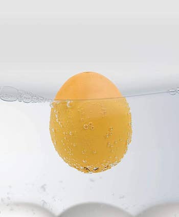 the singing egg timer floating in water with eggs that are cooking