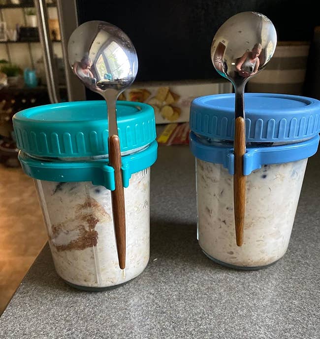 Two jars of overnight oats with spoons attached to them