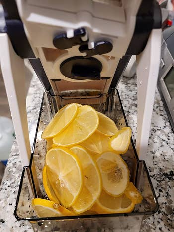 reviewer photo of thinly-sliced lemons in the bowl of the mandoline