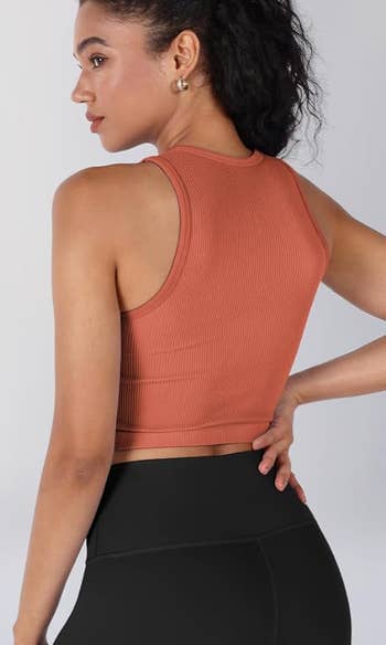 model in a sleeveless orange crop top 