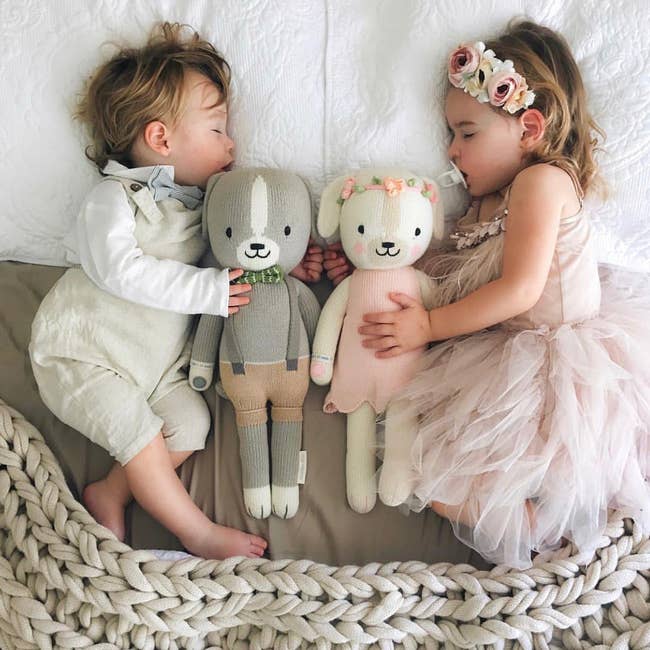 Two children napping with plush bunnies, one in a tulle dress and the other in overalls