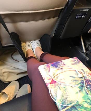 reviewer resting their feet on the in-flight foot hammock