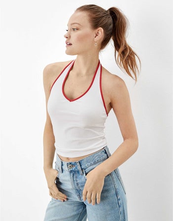 model wearing white halter tank top with red trim