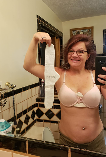 reviewer wearing the white liner under a bra while also holding up another white liner