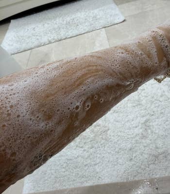Arm covered successful lathered soap, suggesting a skincare oregon shaving merchandise successful a bath setting