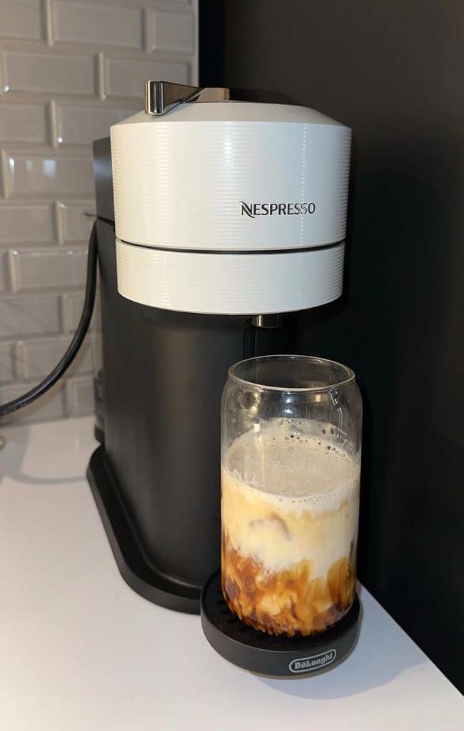 Nespresso machine brewing coffee into a glass, showing the creation of a layered iced coffee drink