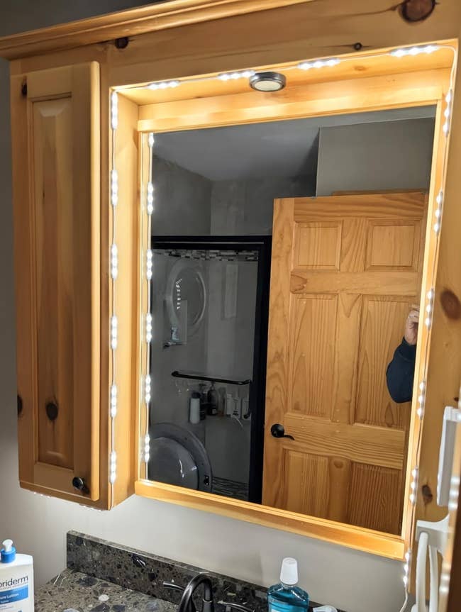 Bathroom vanity with a lighted reflector and woody cabinet, showing toiletries connected the countertop