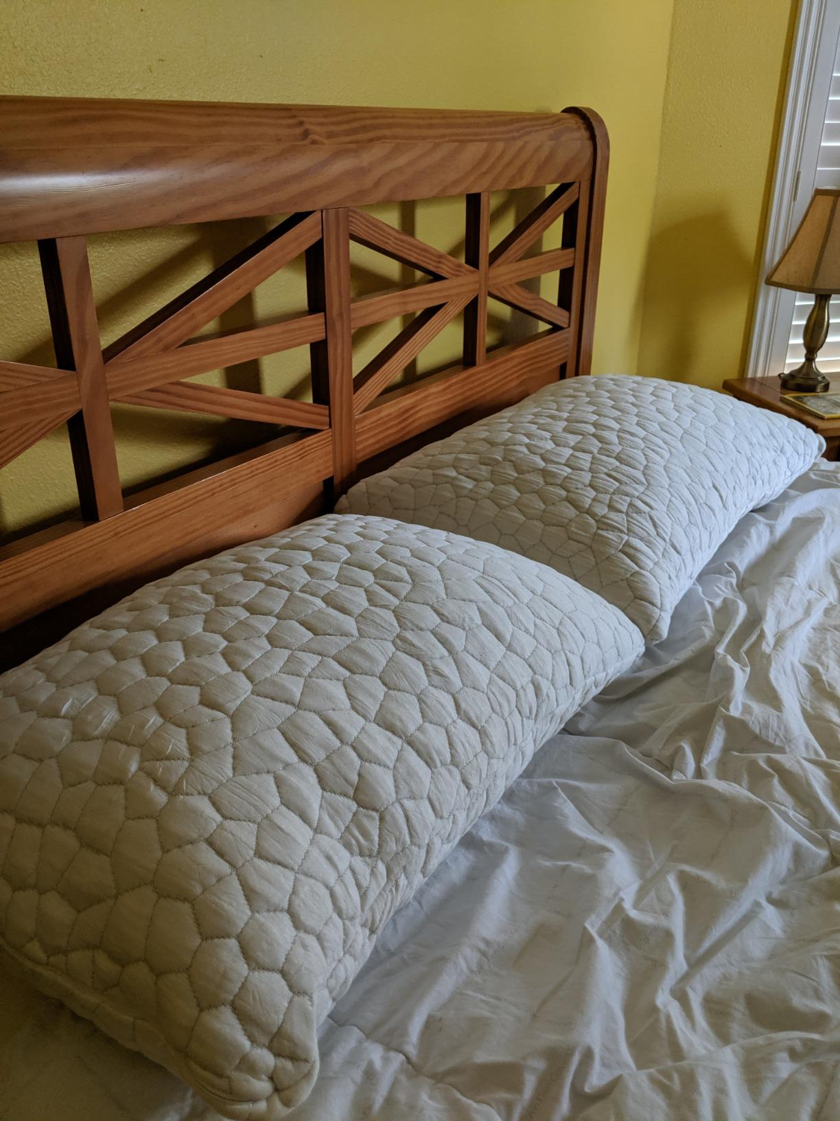 Two ample  pillows with quilted texture connected  a furniture  with a woody  headboard, successful  a chamber  setting