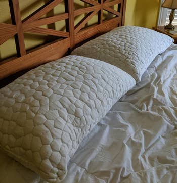 Two ample pillows with quilted texture connected a furniture with a woody headboard, successful a chamber setting
