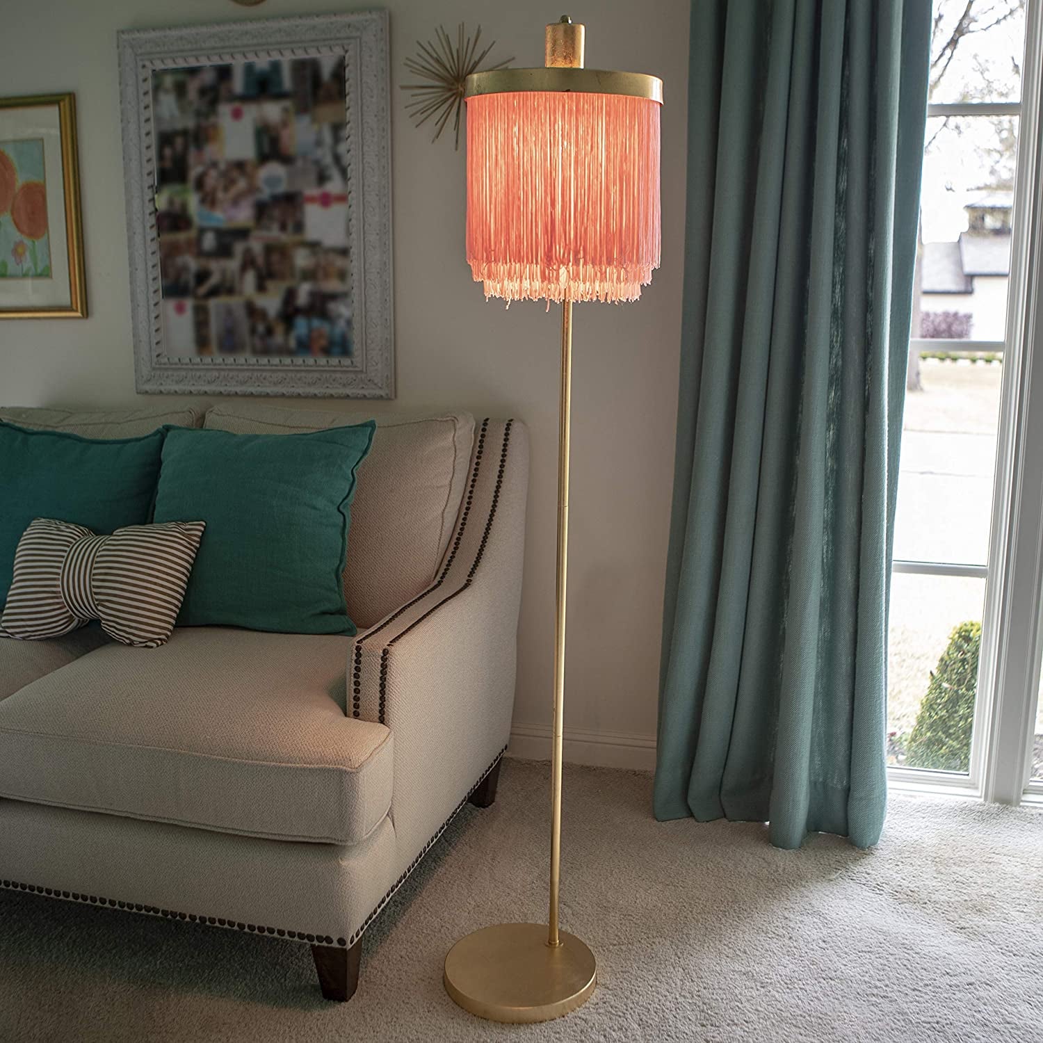 living room with gold tone floor lamp that has a pink fringe shade on it