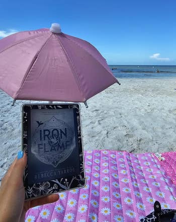 Kindle covered by a pink umbrella