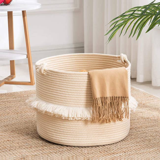 the taupe basket with a blanket hanging off the side