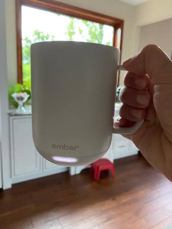 reviewer holding up the white ember mug