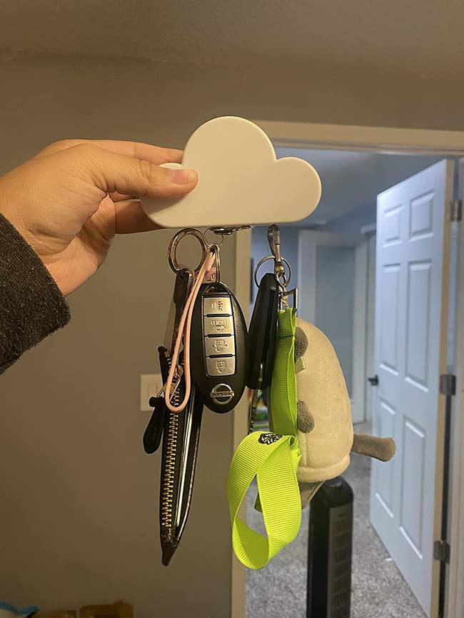 A reviewer holding their cloud magnet that is holding three sets of keys