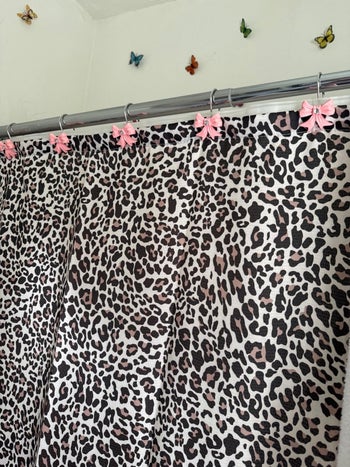 Leopard print curtains with pink bow clips hanging on a metal rod