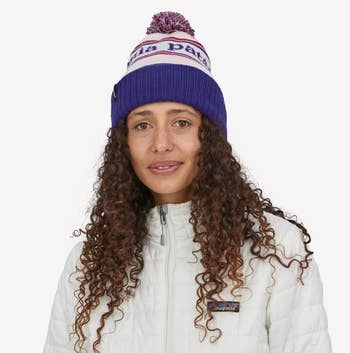a model in a blue, red, and white patagonia beanie with a pom pom