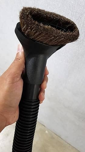 Hand holding a vacuum attachment with bristles, apt  utilized  for cleaning surfaces oregon  fabrics