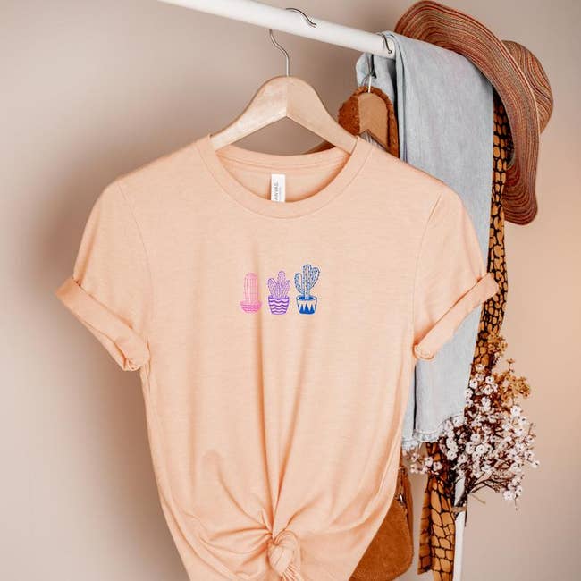 the peach tee with graphic of pink, purple, and blue cactuses
