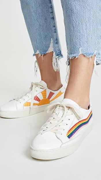 White sneakers with embroidered rainbow along the outsides and embroidered sun in yellow and orange along the insides