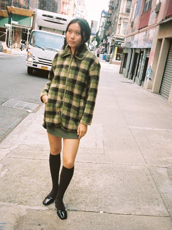 model wearing the green and black plaid sherpa jacket