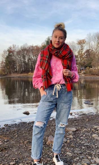 reviewer wearing the distressed jean joggers outside with a scarf