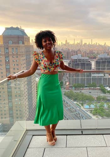 reviewer wearing green skirt on a rooftop overlooking a cityscape
