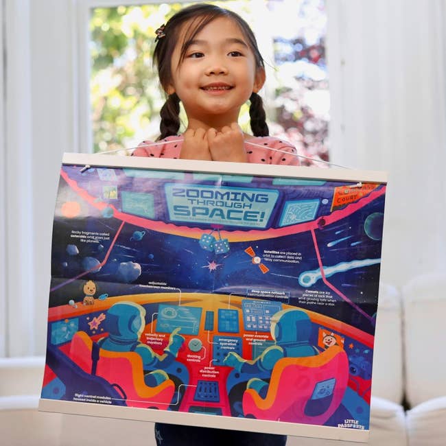 a child holding up a space-themed poster