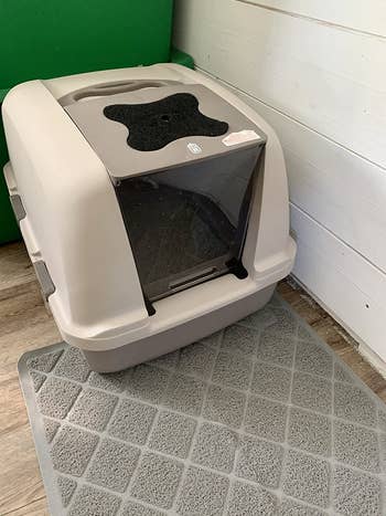 The jumbo litter box set up in a corner with a mat underneath