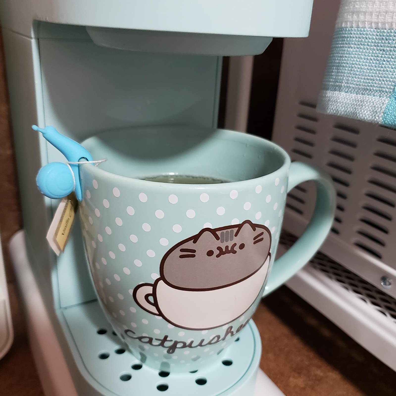 reviewer photo of the blue snail holding a tea bag on the rim of a mug