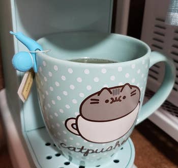 reviewer's blue snail holding a tea bag on the rim of a mug
