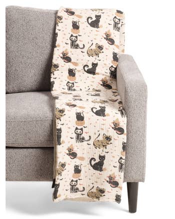 Throw broad  with cute feline  designs draped implicit    armchair