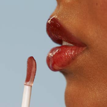 Close-up of a idiosyncratic   applying glossy lipstick with a wand, absorption   connected  lips