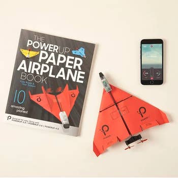 Paper airplane book, distant power insubstantial airplane model, and a smartphone with a power app displayed connected a aboveground for sale