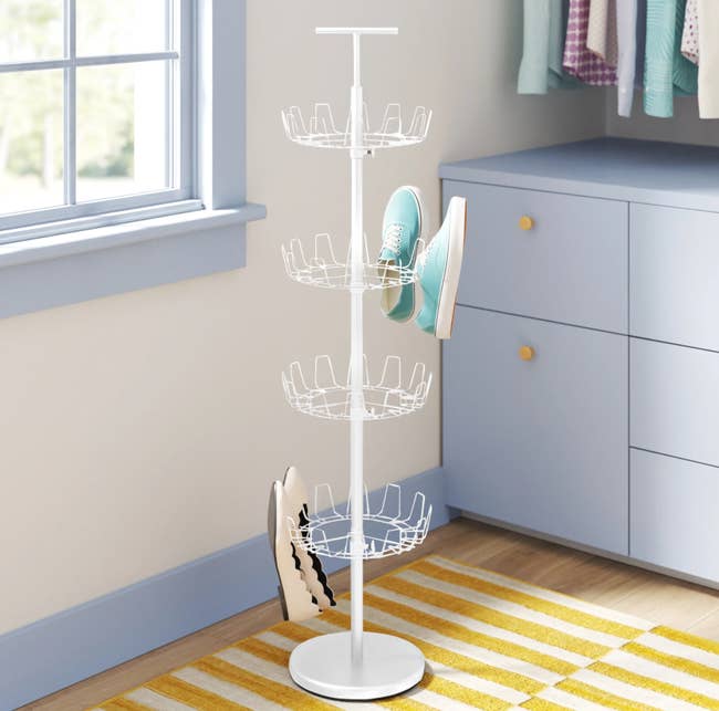 A white tree-shaped shoe rack with four rotating rows with hooks to hold shoes 