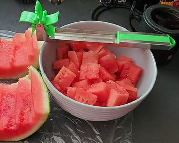 reviewer photo of the watermelon slicer resting on a bowl of watermelon cubes