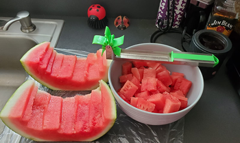 reviewer photo of the watermelon slicer resting on a bowl of watermelon cubes