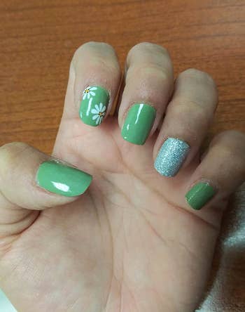 reviewer with green floral nail wraps on