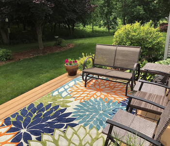 reviewer photo of the blue, green, and orange rug on an outdoor patio
