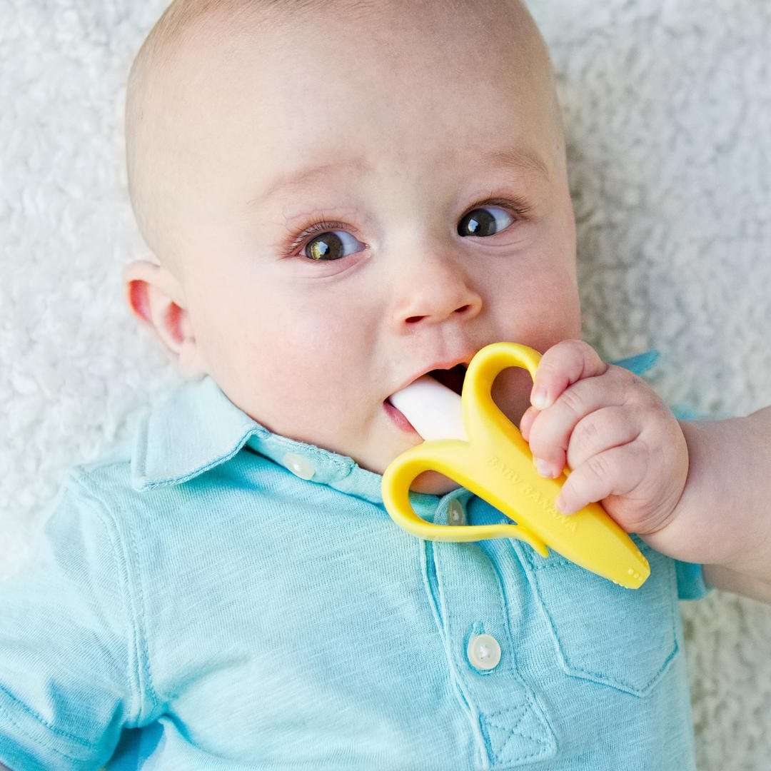 a baby chewing on a banana-shaped teether